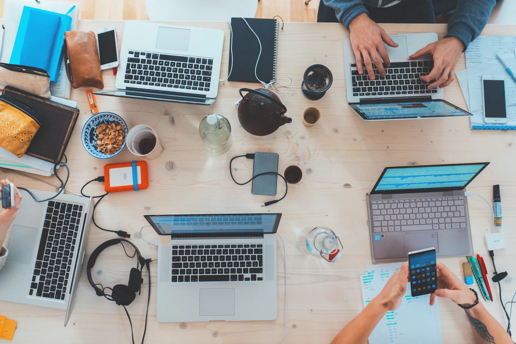 An overhead view of laptops and people working together around a shared table